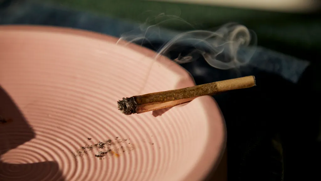 Cigarette au CBD fumante posée sur un cendrier