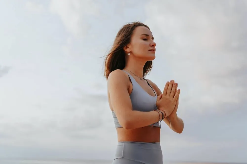 A woman meditates outdoors with her hands together