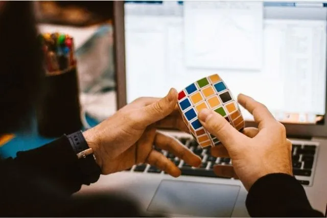 Une personne manipule un Rubik’s Cube devant un ordinateur