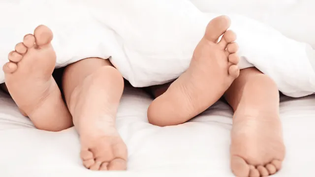 Zwei Personen liegen unter einer Decke, ihre Füße sind sichtbar