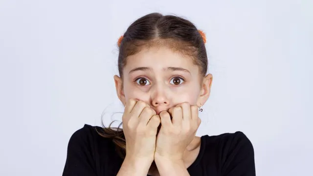 Ein ängstliches Mädchen kaut an seinen Nägeln