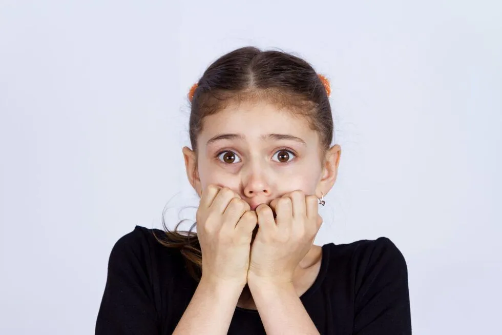 An anxious little girl bites her nails