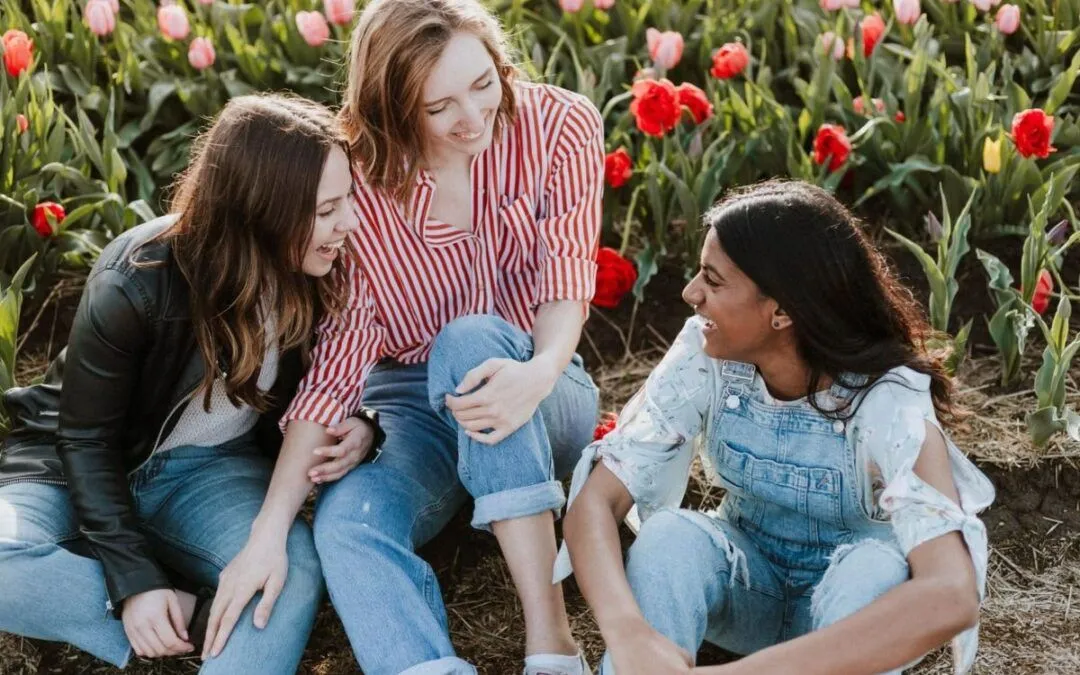 Three young women talk in a flower garden