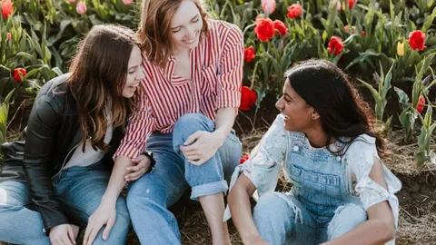 Three young women talk in a flower garden