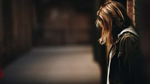 A woman alone with her head bowed in a dark room