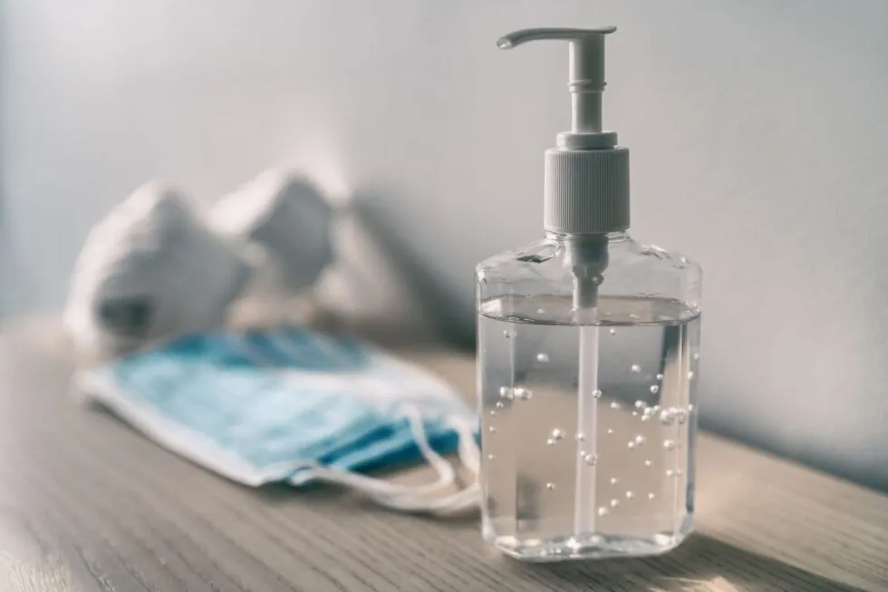 Bottle of hand sanitizer with a mask in the background