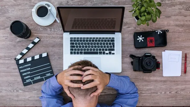 Eine überforderte Person an einem unaufgeräumten Schreibtisch