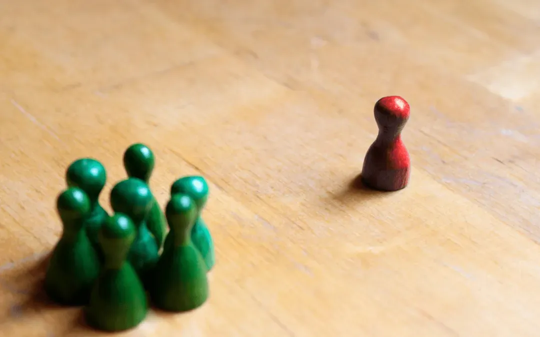 A lone red pawn facing a group of green pawns