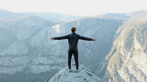 A person standing on a cliff overlooks a valley