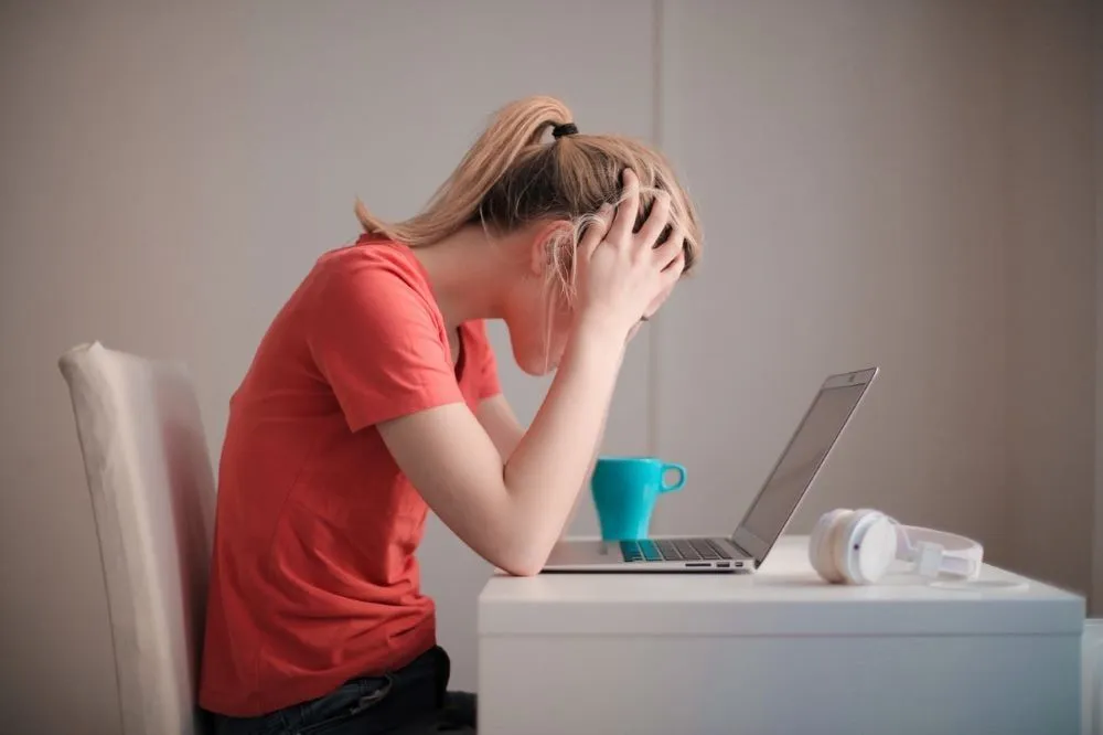 Une femme stressée se tient la tête devant son ordinateur