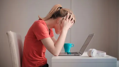 Eine gestresste Frau hält sich vor ihrem Computer den Kopf