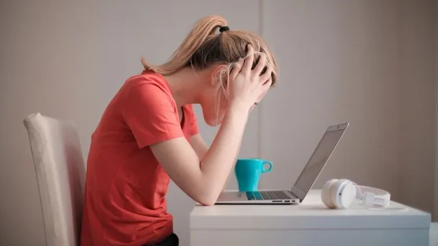 Eine gestresste Frau hält sich vor ihrem Computer den Kopf