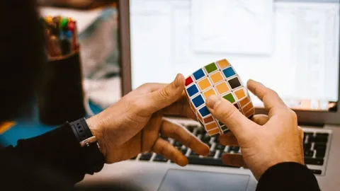 Eine Person löst einen Rubik-Würfel vor einem Computer