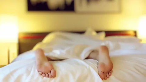 Two people lying under a duvet with their feet visible