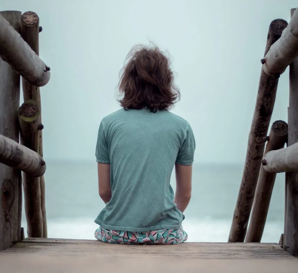 An isolated person sits between two railings