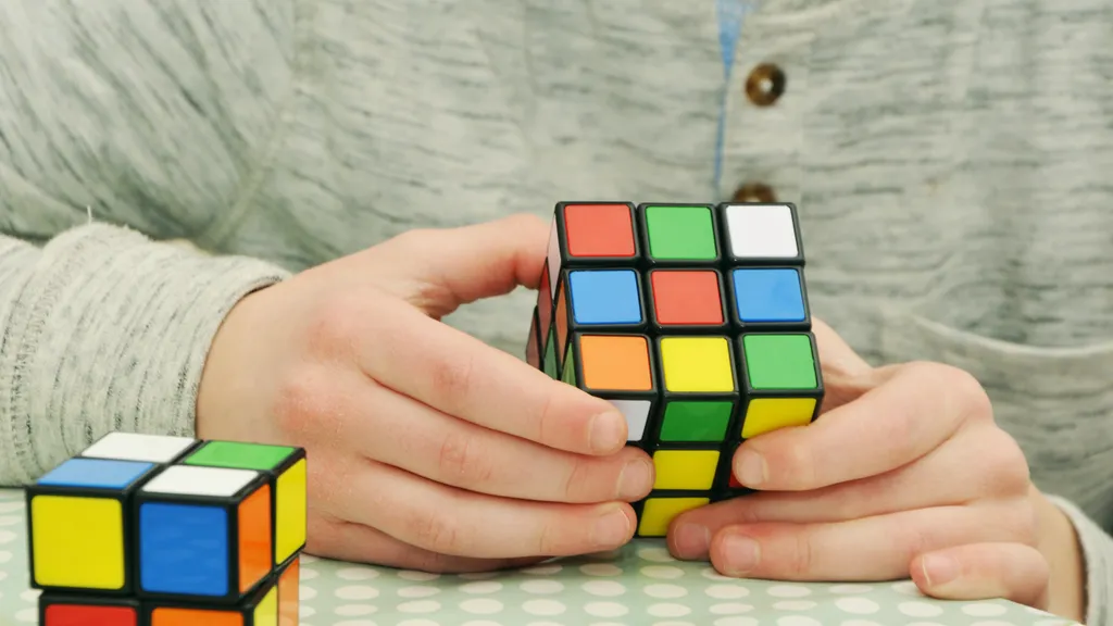 Une personne manipule un Rubik’s Cube, avec un second cube posé sur la table