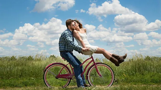 Ein Paar küsst sich auf einem Fahrrad in einem Feld