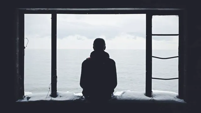 Silhouette einer Person allein vor einem großen Fenster
