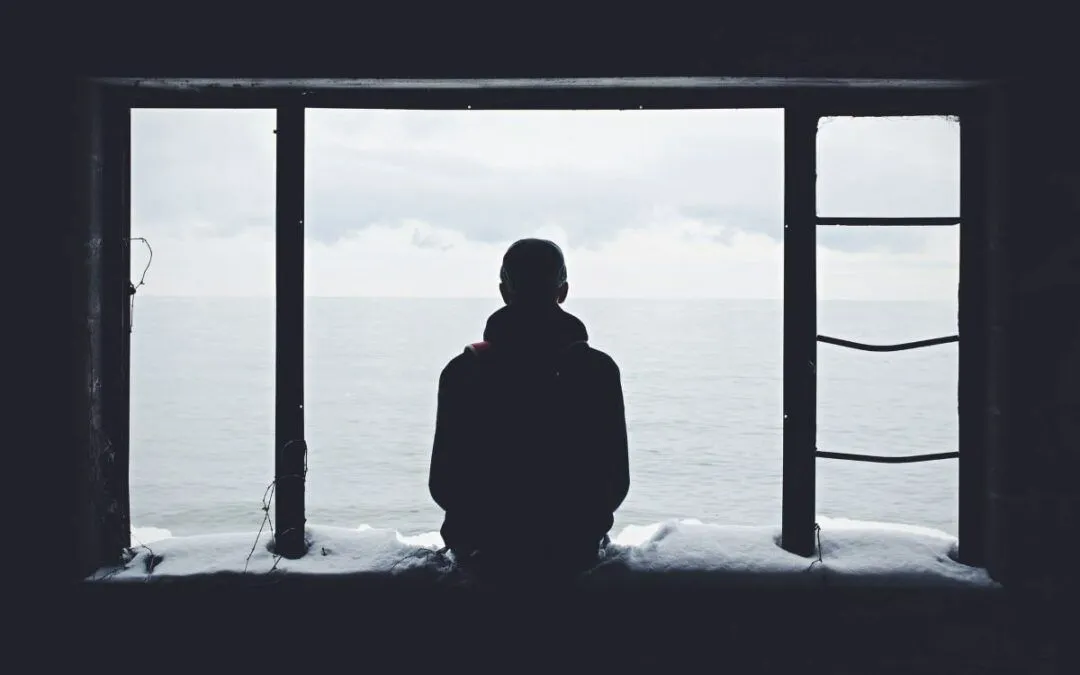 Silhouette d’une personne seule devant une grande fenêtre