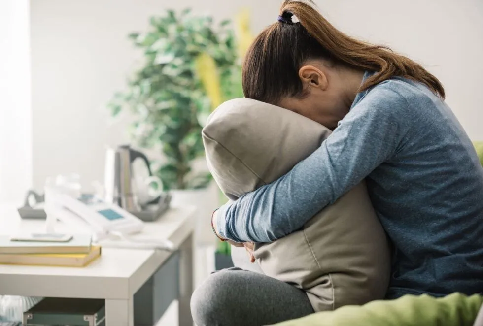 A curled-up woman hugs a cushion