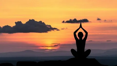 Silueta meditando frente a una puesta de sol
